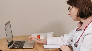 Physician in White Coat Using Her Laptop