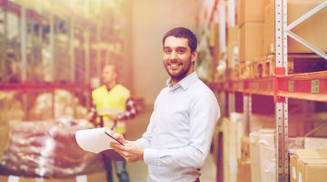 happy businessman or supervisor with clipboards at warehouse