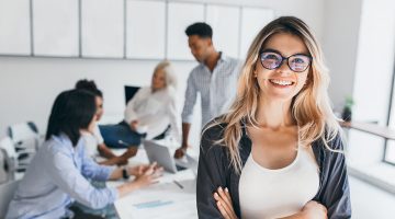 Blonde female executive posing with smile and arms crossed during brainstorm with managers