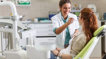 Female dentist in dental office talking with female patient