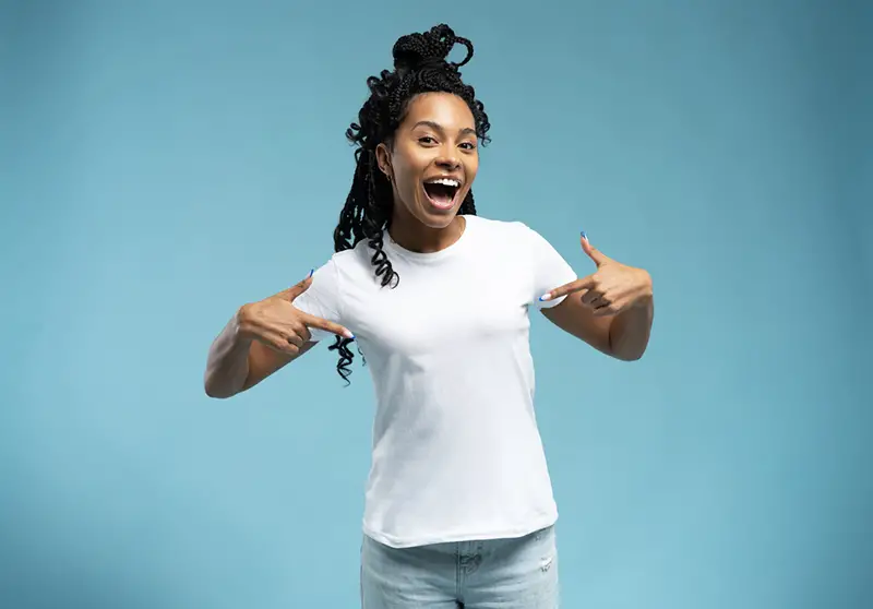 Smiling African American woman wearing white t-shirt pointing finger at her t-shir