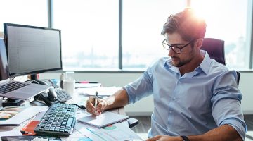Entrepreneur writing notes sitting at his desk