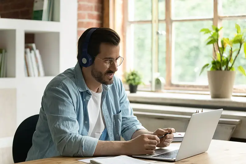 Male employee in headphones use laptop have webcam digital conference with customer