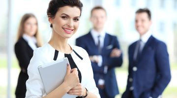 Business woman standing in foreground with a tablet in her hands