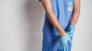 Male doctor putting on sterile gloves