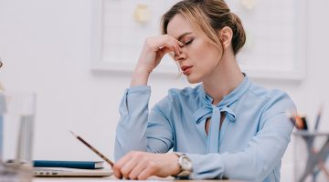 Exhausted adult businesswoman sitting at workplace