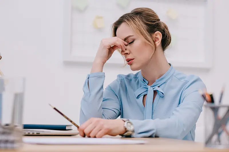 Exhausted adult businesswoman sitting at workplace