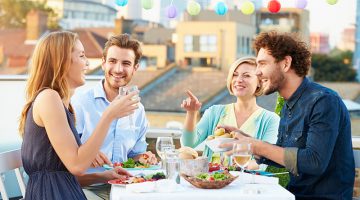 Group Of Friends Eating Meal On Rooftop Terrace