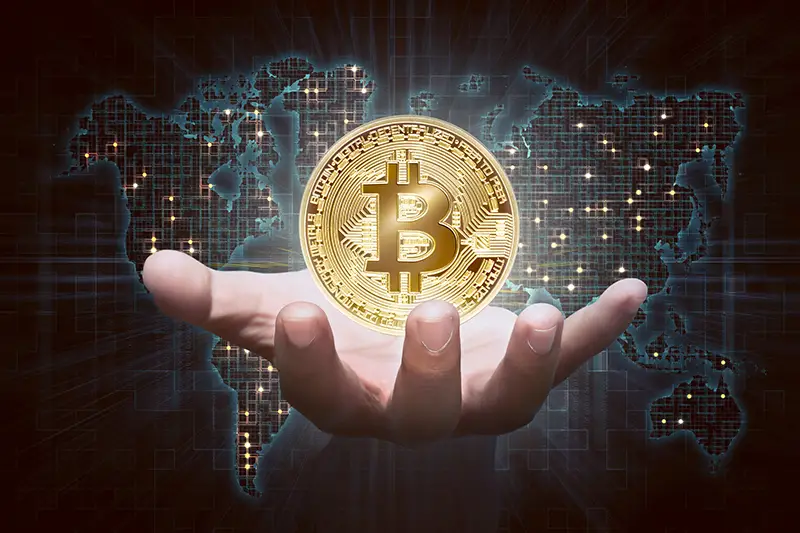 Man hands showing golden bitcoin as virtual money on digital world map background