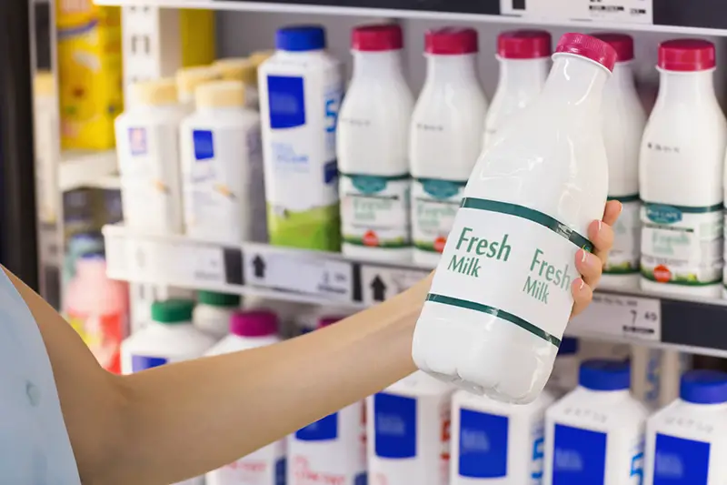 A woman having on her hands a fresh milk bottle in supermarket