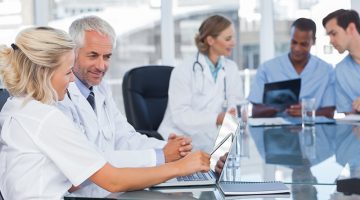 Two smiling doctors using laptop