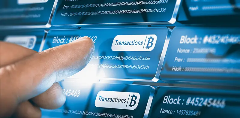 Finger pressing a block chain block with the text transaction