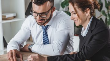 Happy financiers stacking coins on table in office