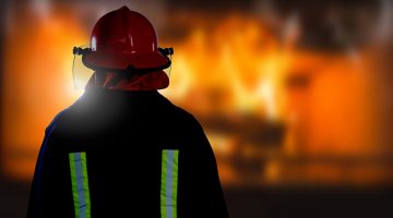 Digital composite of Firefighter in front of burning fire