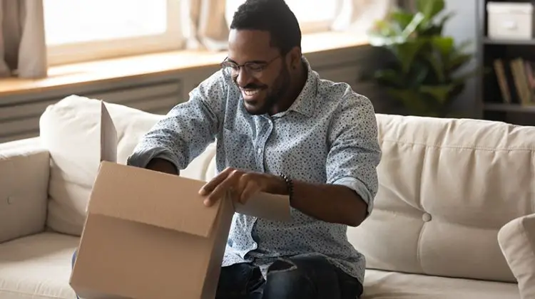 happy ethnic male consumer unpack parcel receive retail purchase