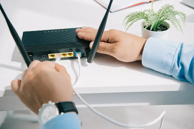 Partial view of businessman plugging router on ethernet wire