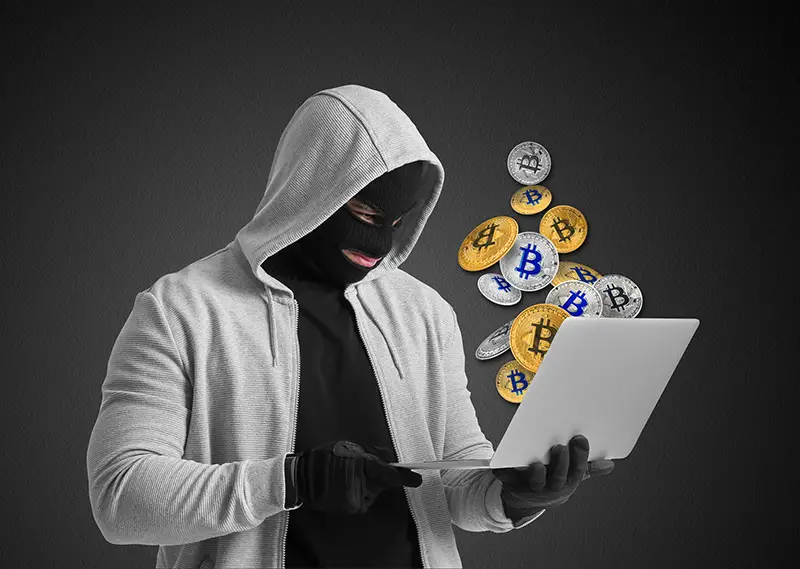 Male hacker with laptop and many bitcoins on dark background