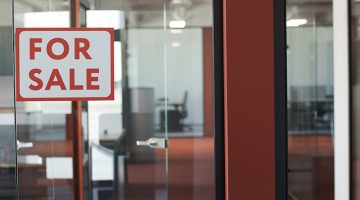 For Sale sign on glass door of empty office rental, copy space