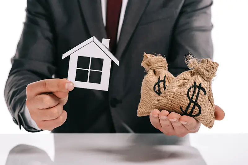 Cropped view of mortgage broker holding paper house and money sack