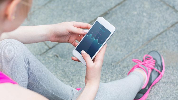 Athletic lady in uniform and sneakers use smartphone to check activity on screen during rest