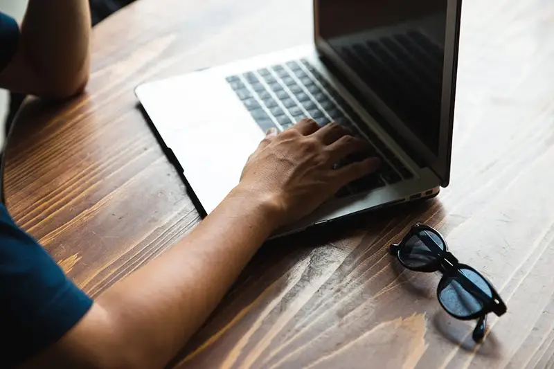 Cropped man using laptop on the top of wooden table