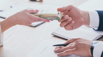 Cropped view of woman giving money to manager