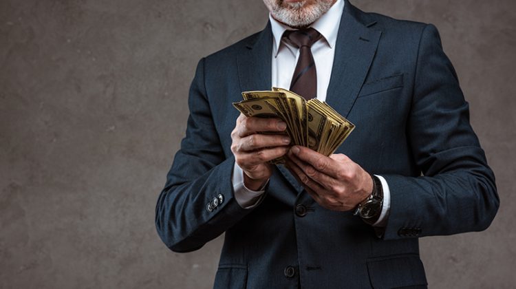 Cropped view of businessman in suit holding dollars