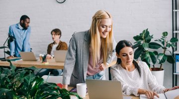 Businesswoman pointing at textbook to colleague