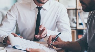 Insurance agent nad male client signing an insurance for a business