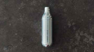 Top view of a nitrous oxide capsule on a concrete surface