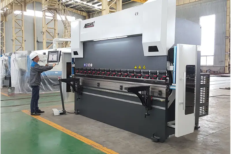 Man wearing white safety helmet operating CNC machine