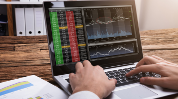 Close-up Of A Stock Market Broker's Hand looking at the graphs