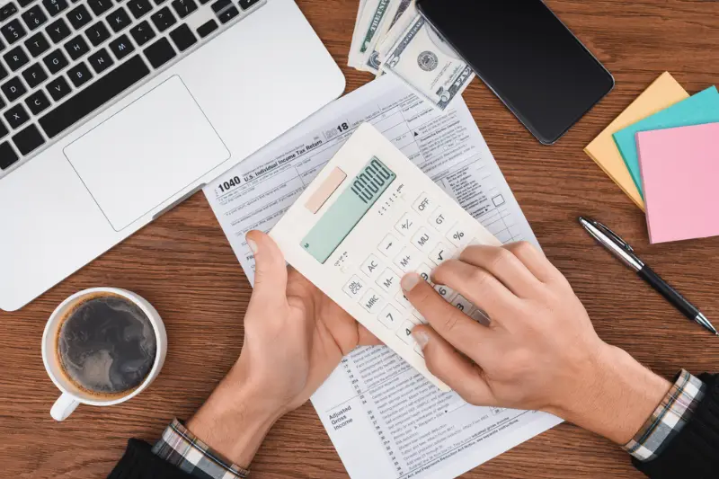 Cropped view of man using calculator with tax form