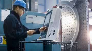 Factory worker is programming a CNC milling machine
