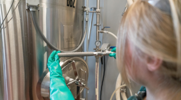Person Wearing Gloves While Fixing Distillation Tank