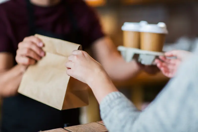 Man or bartender serving customer at coffee shop for takeaway orders