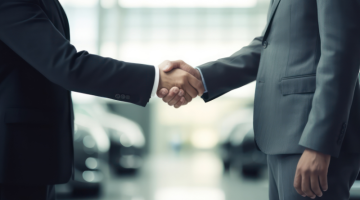 Car dealer shaking hands with customer in car shop