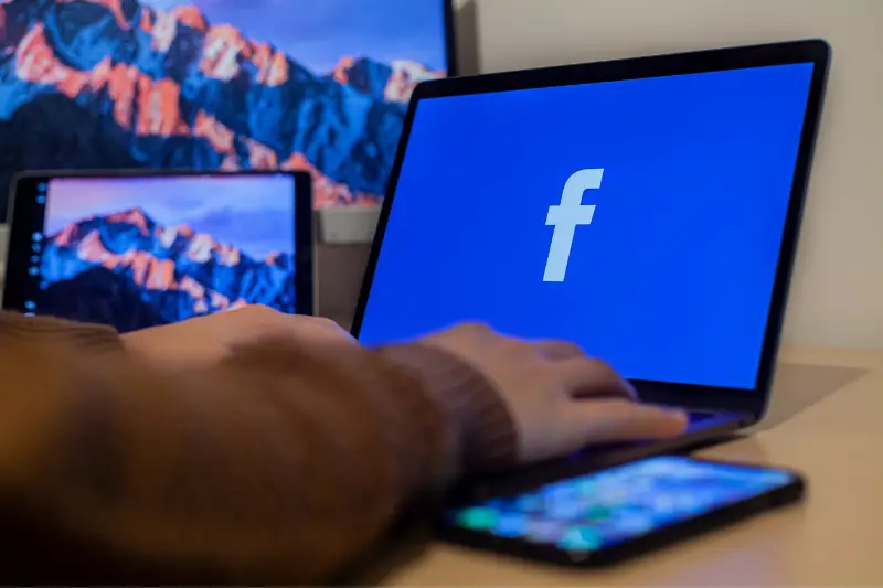 Person using laptop with facebook icon