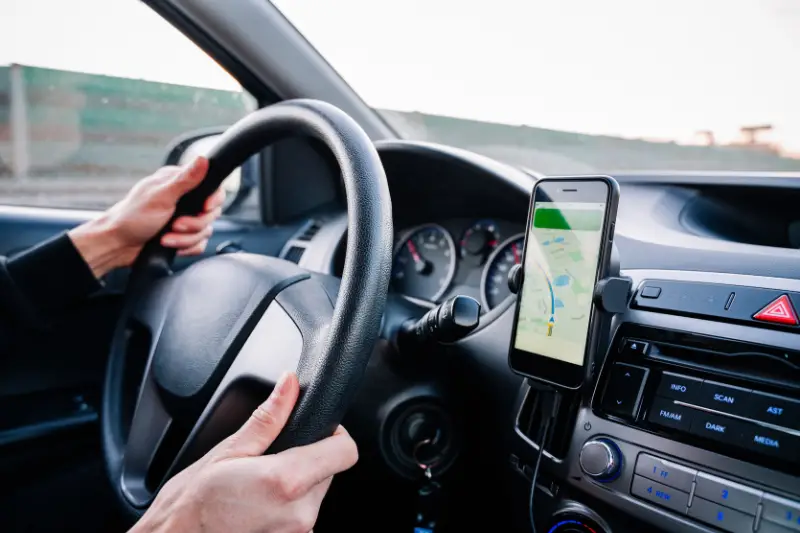 Global positioning system on smartphone screen in auto car on travel road. GPS vehicle navigator driver device.