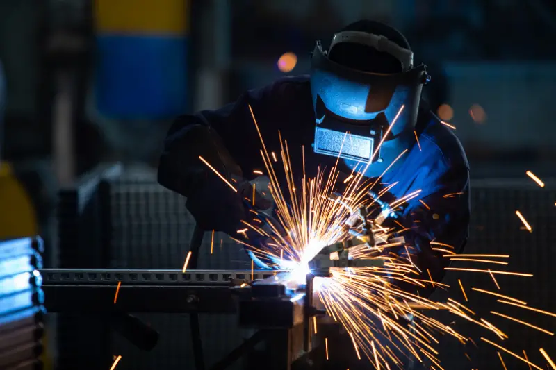 Workers wearing industrial uniforms and Welded Iron Mask at Steel welding plants, industrial safety first concept.