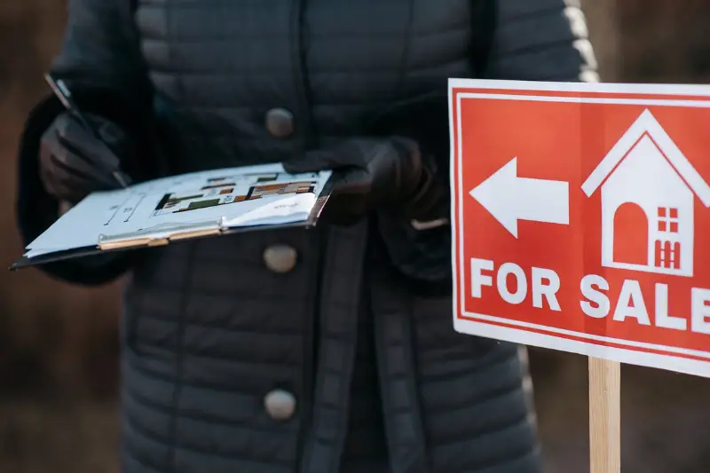 Man in Black Jacket Holding Red and White No Smoking Sign