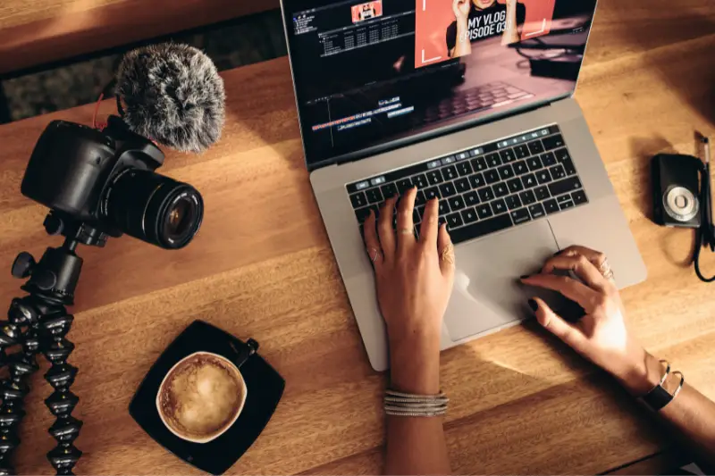 Young female vlogger editing her vlog on computer.