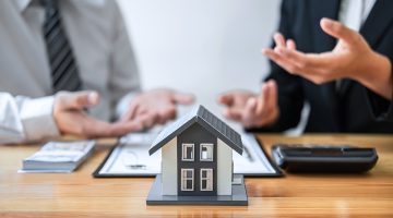 Estate agent are presenting home loan and giving house to client after discussing and signing