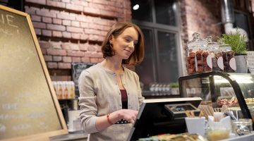 Happy woman or barmaid with cashbox at cafe
