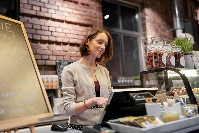 Happy woman or barmaid with cashbox at cafe