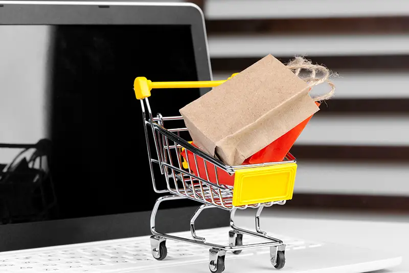 Online shopping concept. Shopping cart, laptop on the desk