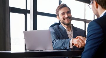 Young boss hiring new colleague shaking hands after successful job interview
