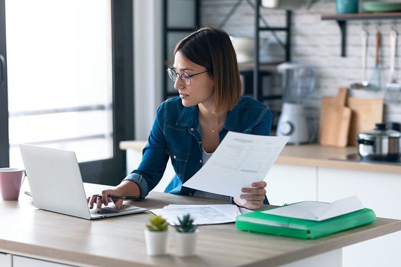 Business woman working with computer while consulting invoices and documents