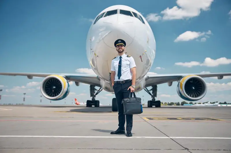 Cheerful male pilot standing outdoors in airfield