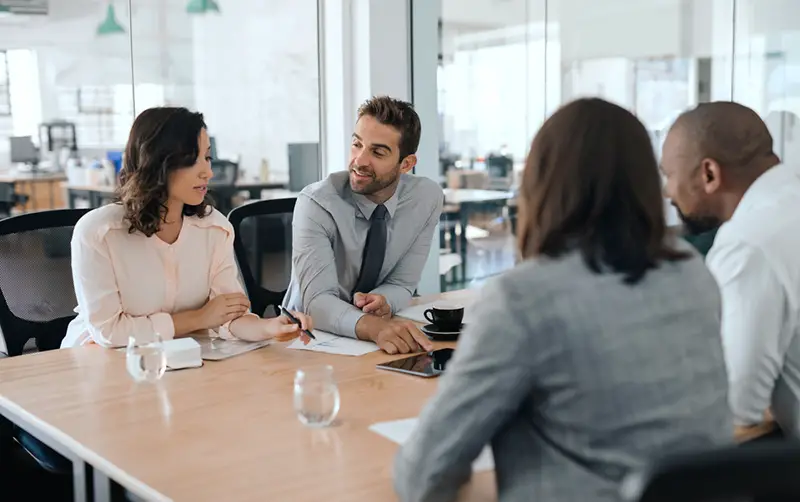 Smiling group of diverse businesspeople sitting together around a table in an office